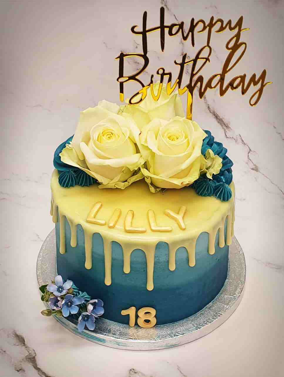 Blauwe ombre driptaart voor Lilly (18) met witte rozen en gouden Happy Birthday-topper