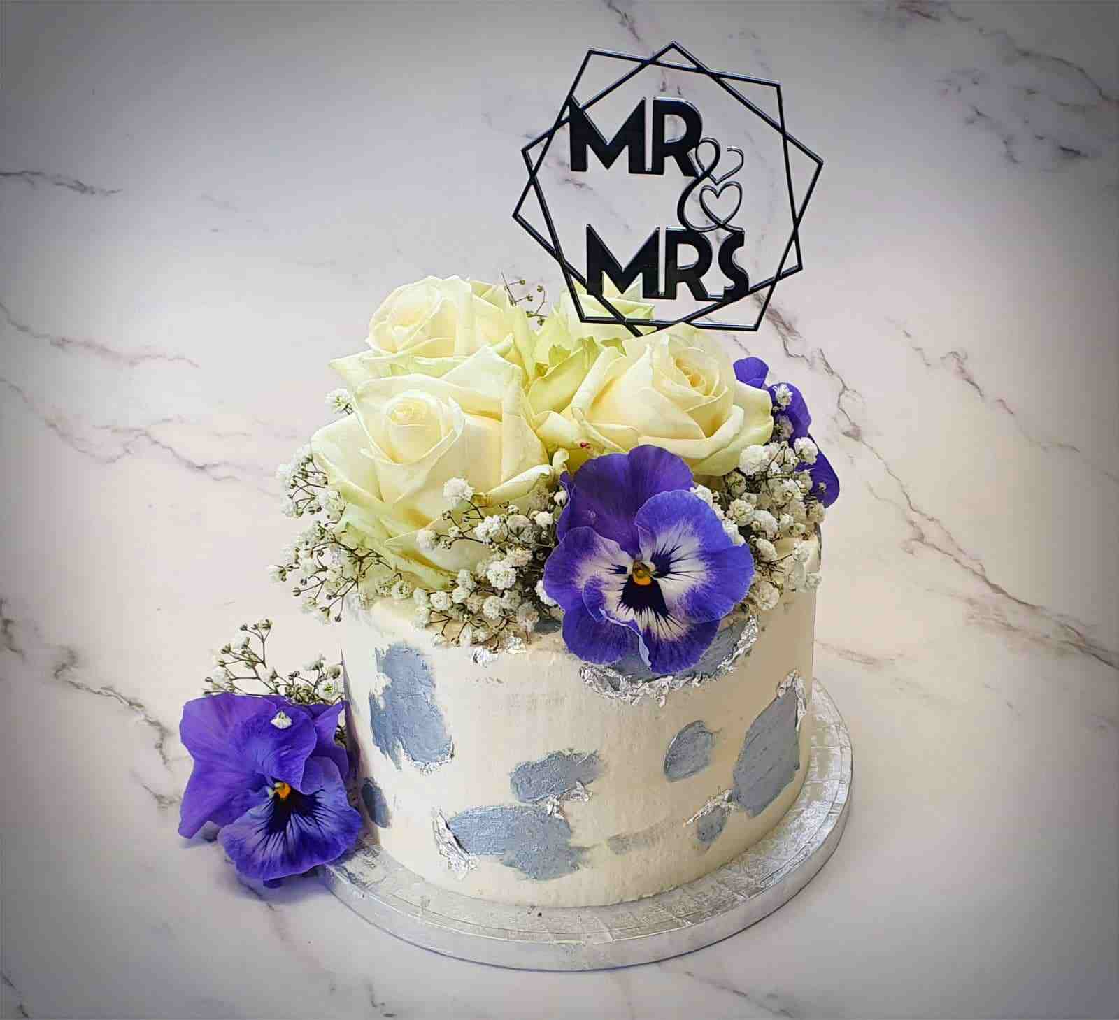 Witte bruidstaart met Mr & Mrs-topper, witte rozen, paarse violen en zilveren accenten