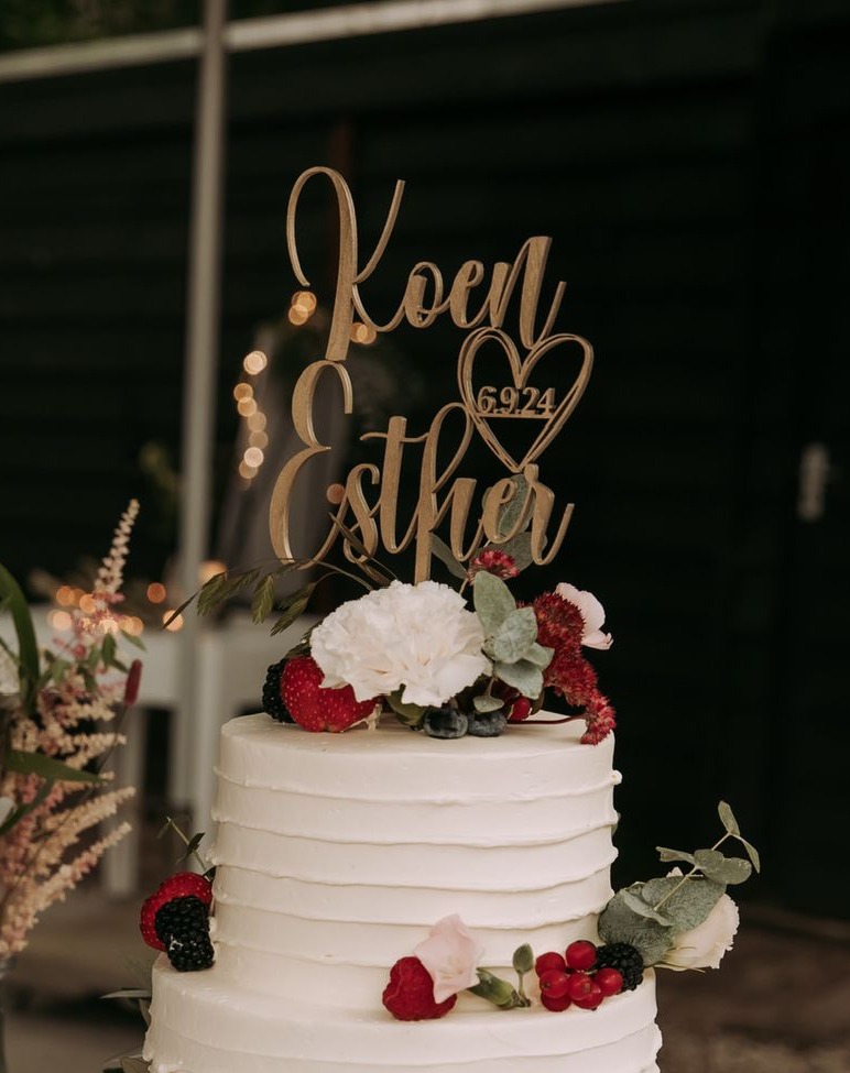 Witte bruidstaart met vers rood fruit, bloemen en houten naamtopper met trouwdatum