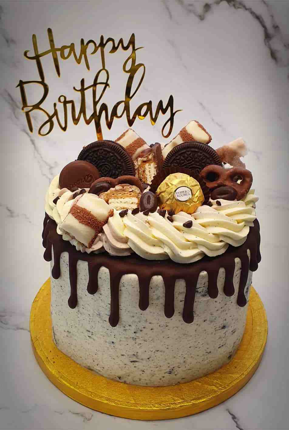Cookies-en-cream driptaart met Oreo's, Ferrero Rocher en gouden Happy Birthday-topper