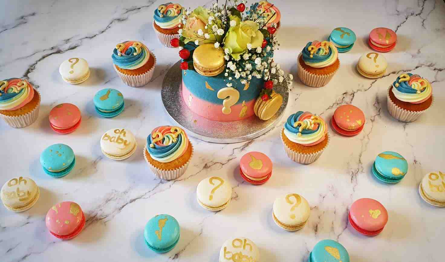 Gender reveal sweet table met blauw-roze taart met vraagteken, cupcakes en macarons
