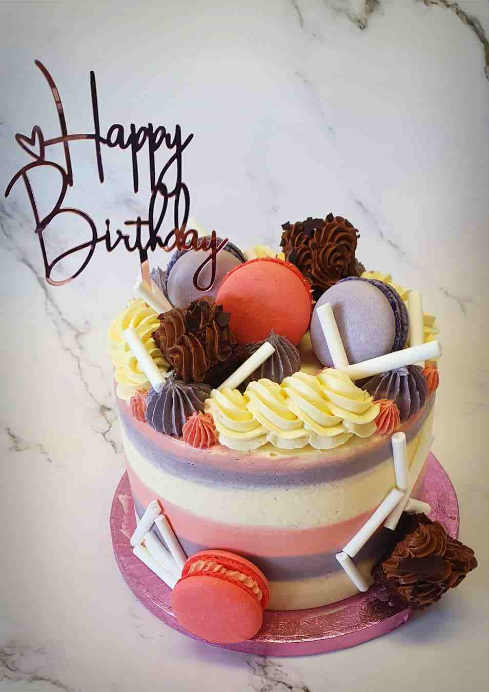 Gestreepte taart in roze, paars en geel met macarons, toefjes en chocolade