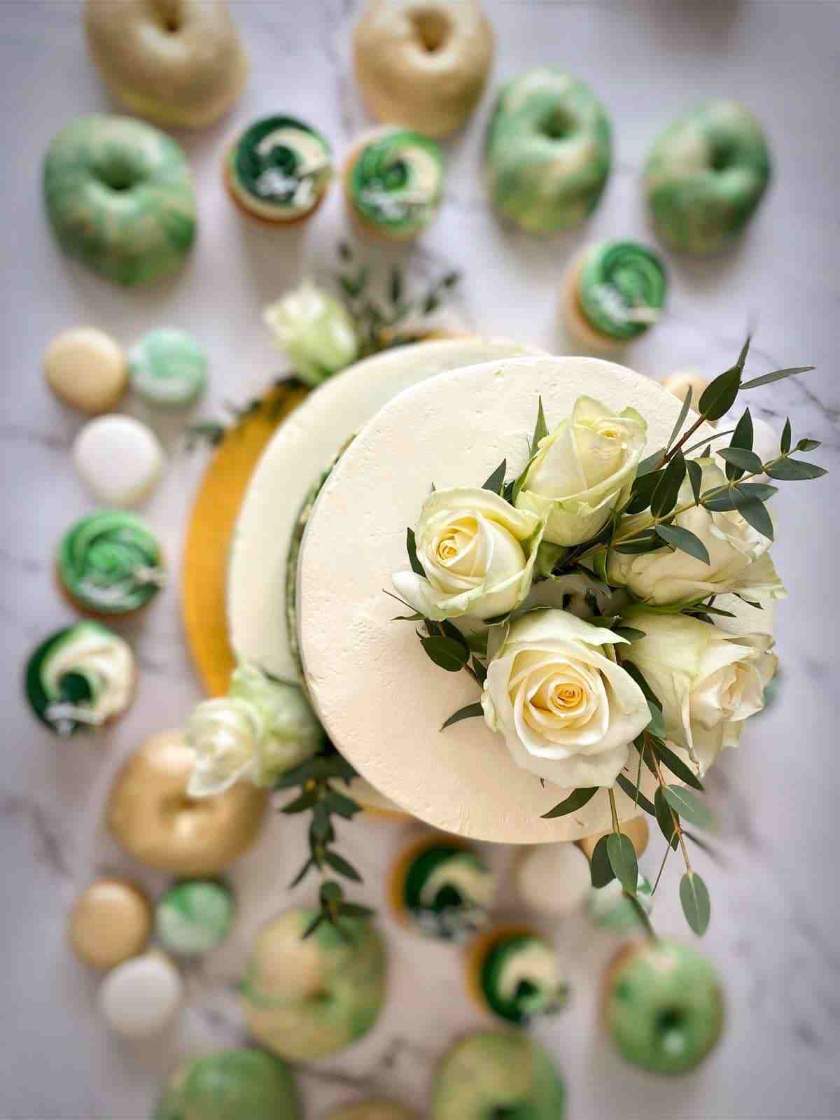 Sweet table in groen en goud met taart met witte rozen, donuts, cupcakes en macarons